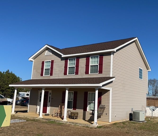 A house with red shutters and a porch on a sunny day
