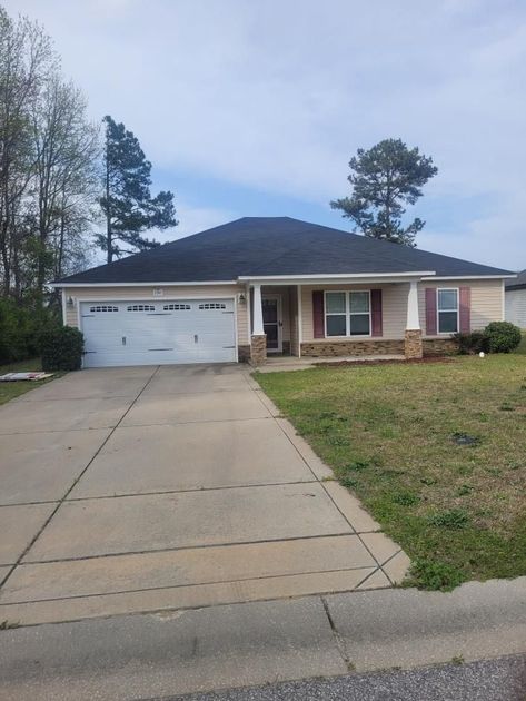 A house with a black roof and a white garage door is for sale.