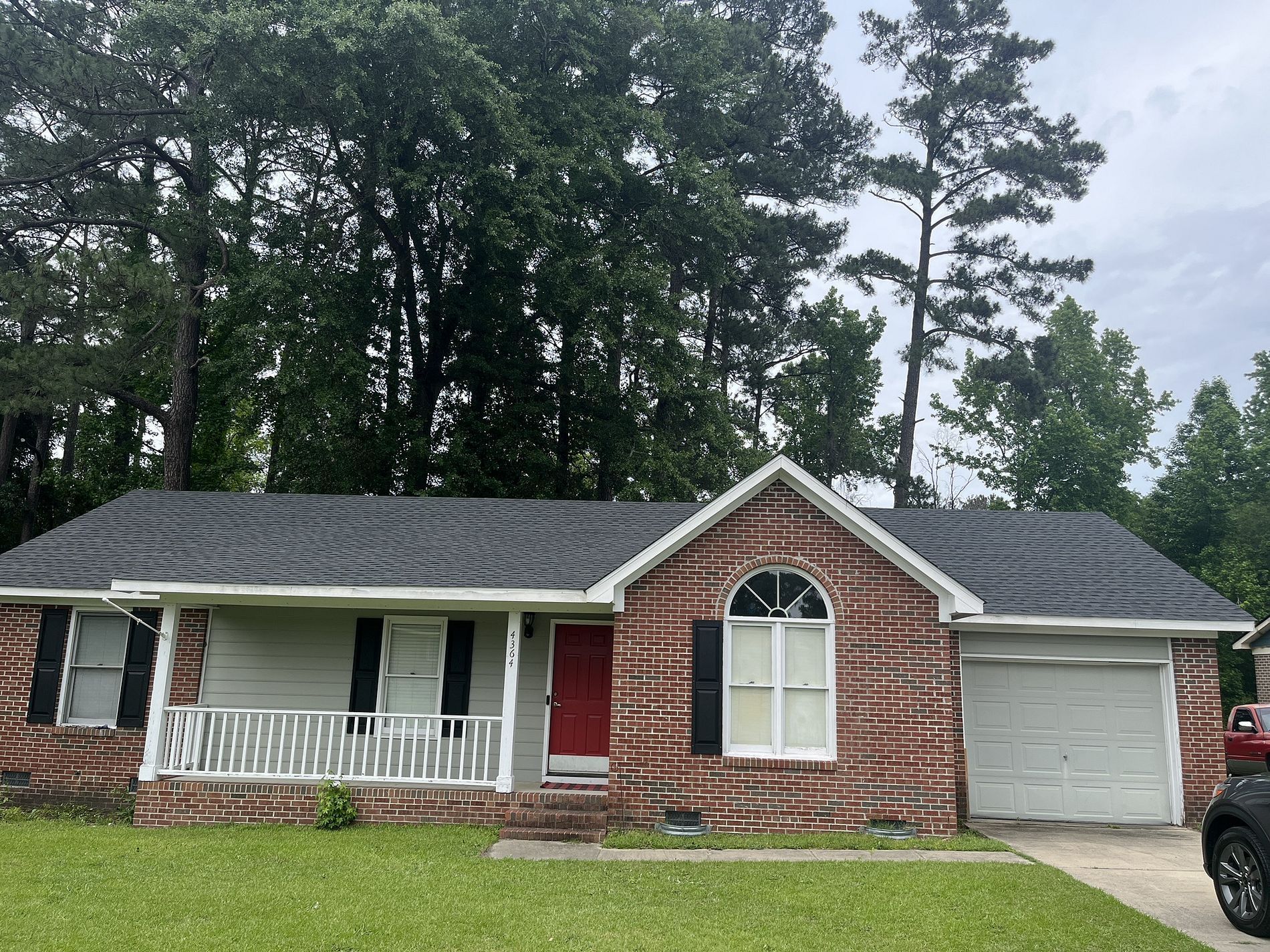 A brick house with a car parked in front of it.