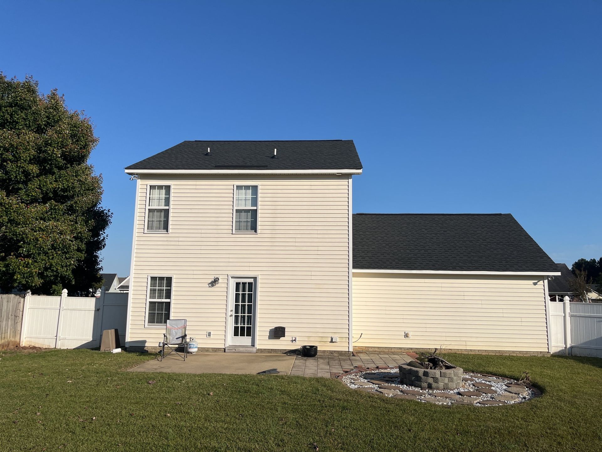 The back of a house with a fire pit in the backyard.