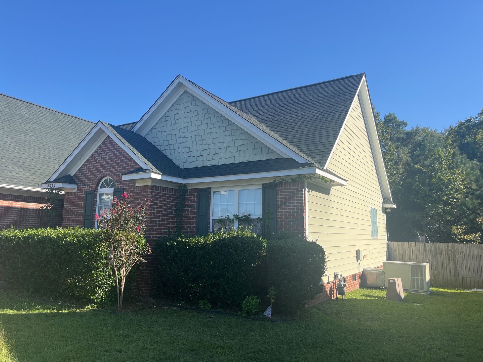 A brick house with a gray roof and white siding