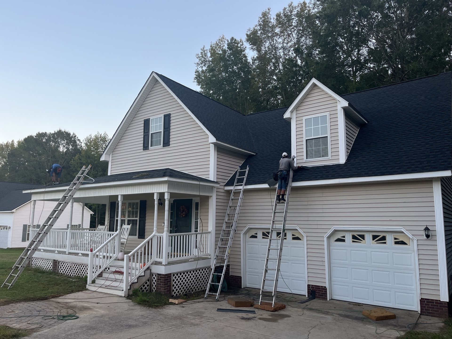 A man on a ladder is painting the roof of a house.