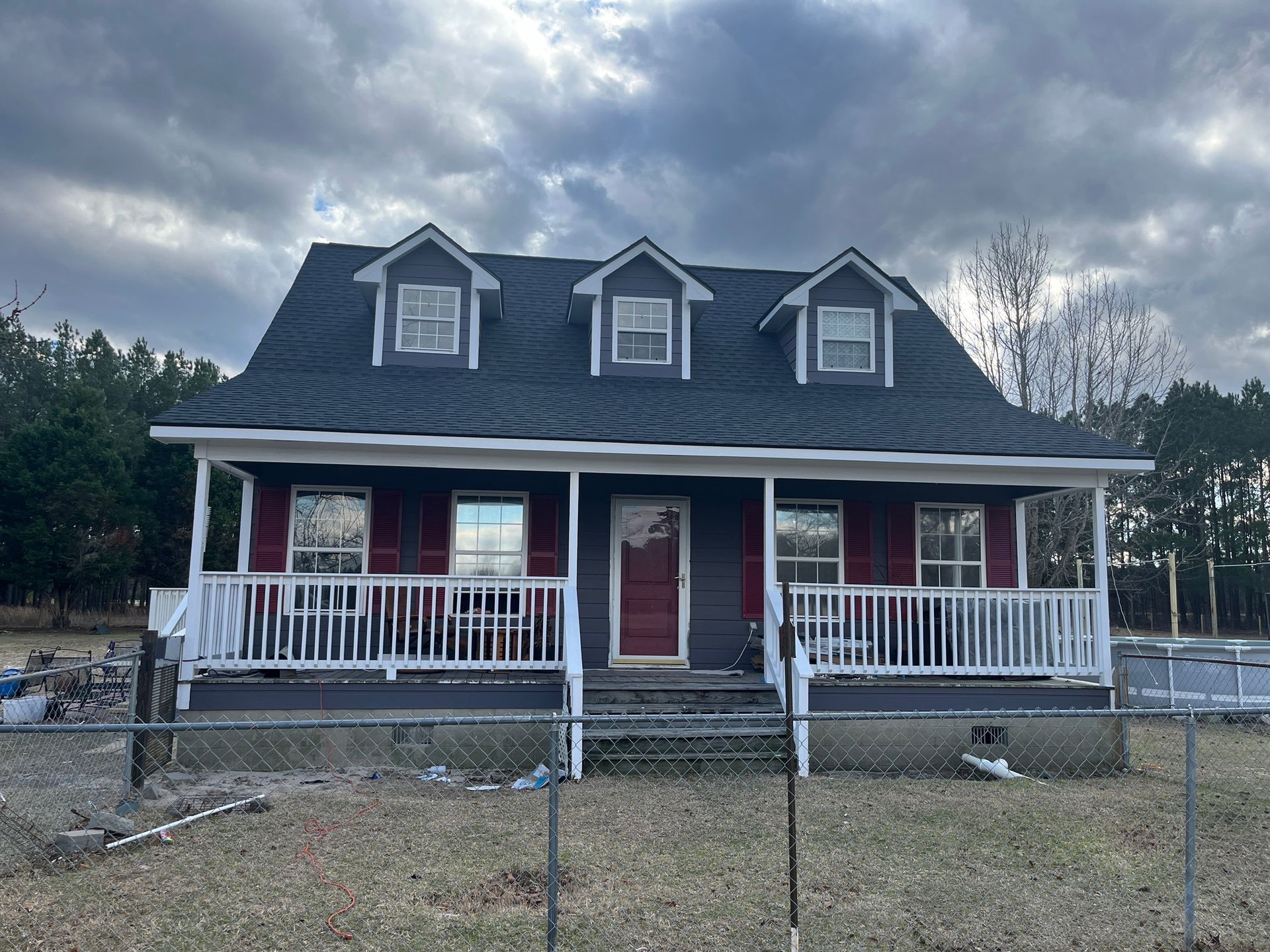 A red house with a black roof and a white porch.