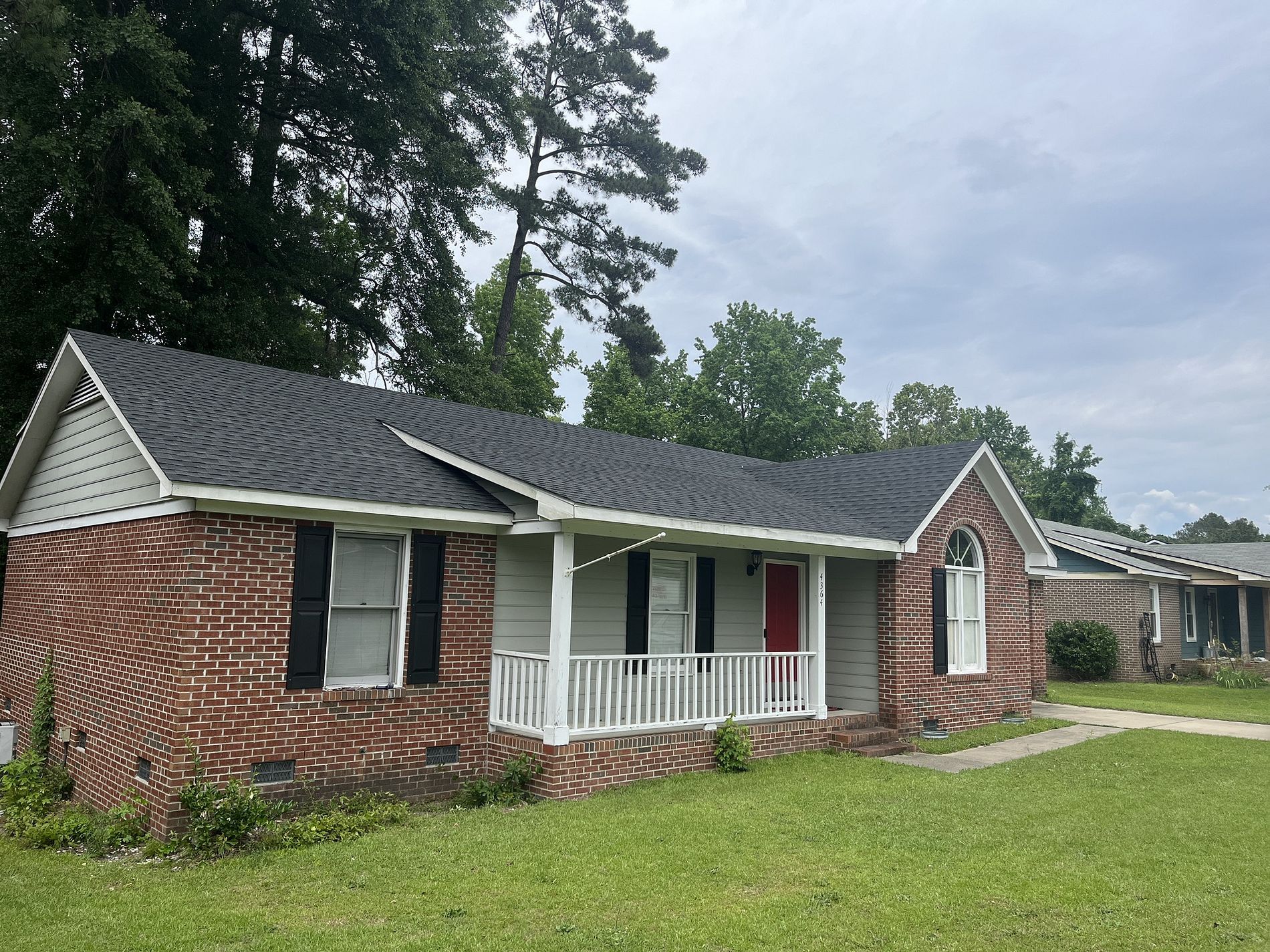 A brick house with a porch and black shutters