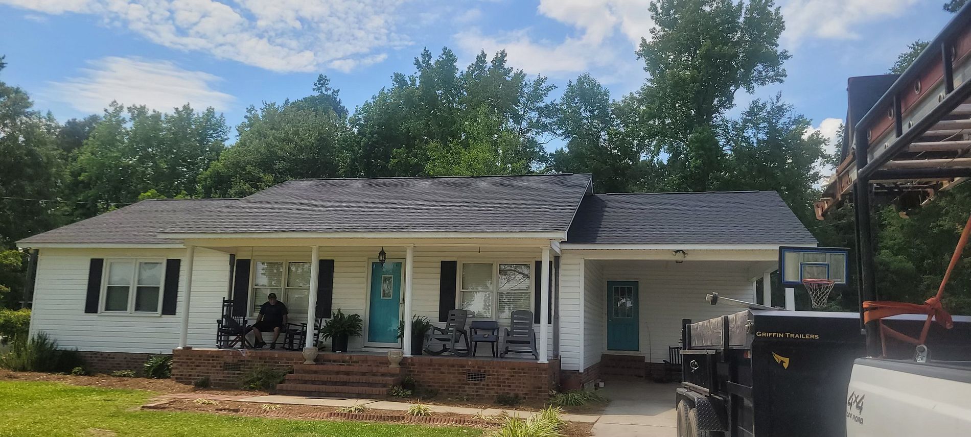 A white house with a black roof and a porch.