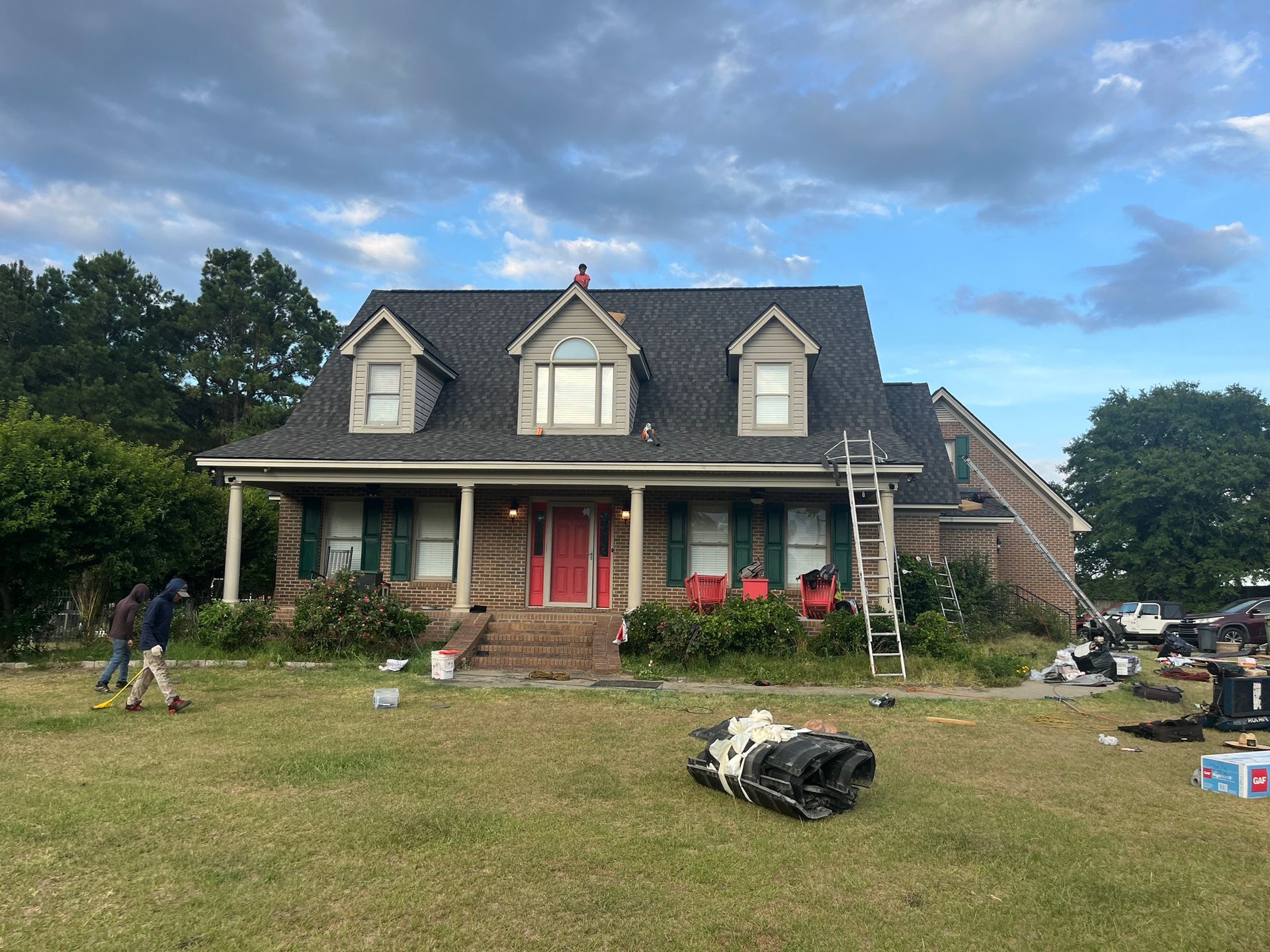A house with a red door and a black roof is being painted.