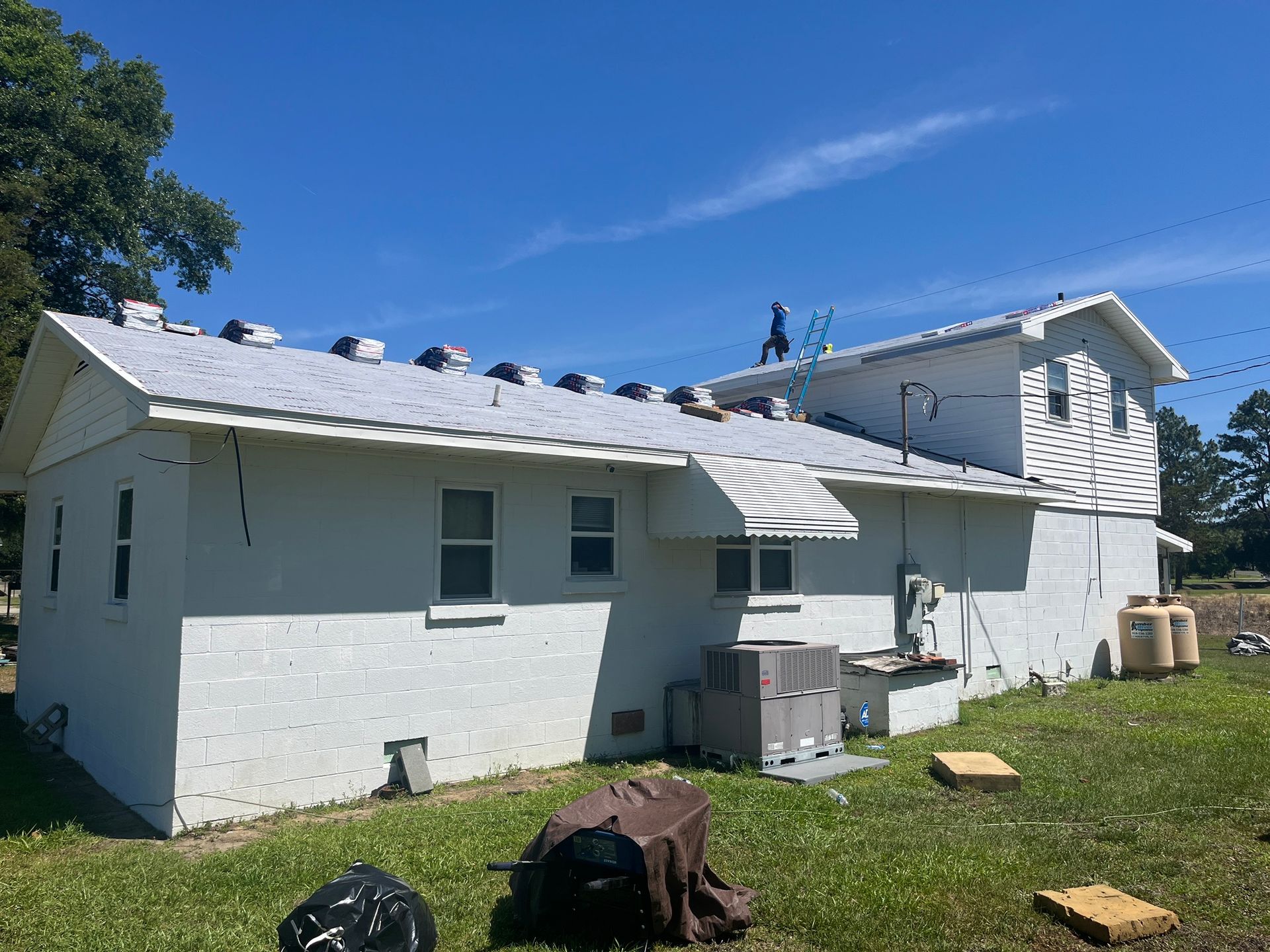 A man is working on the roof of a white house.
