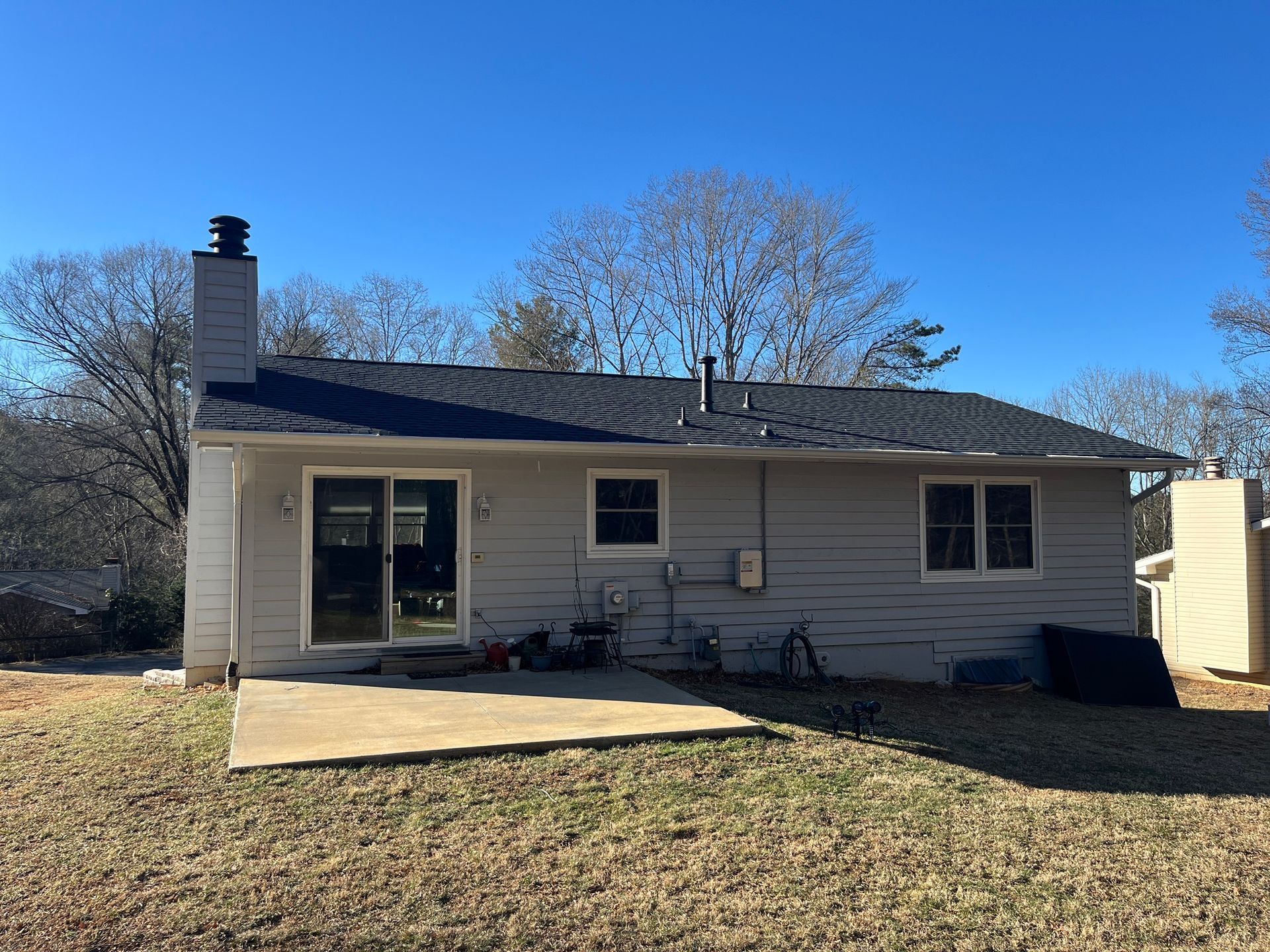 The back of a house with a sliding glass door and a chimney.