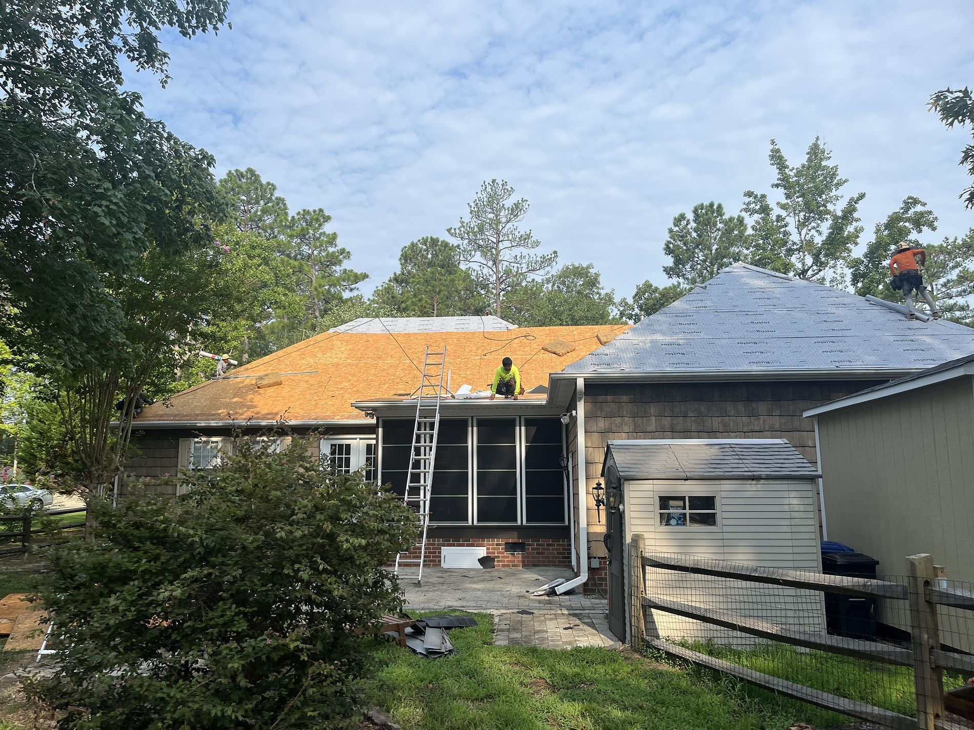Two men are working on the roof of a house.