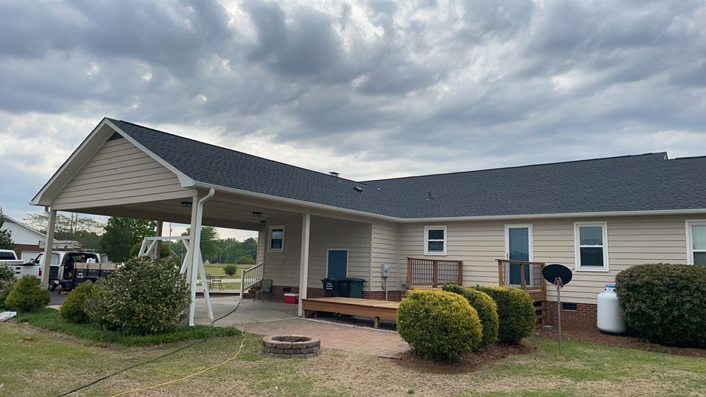 A house with a porch and a fire pit in front of it.