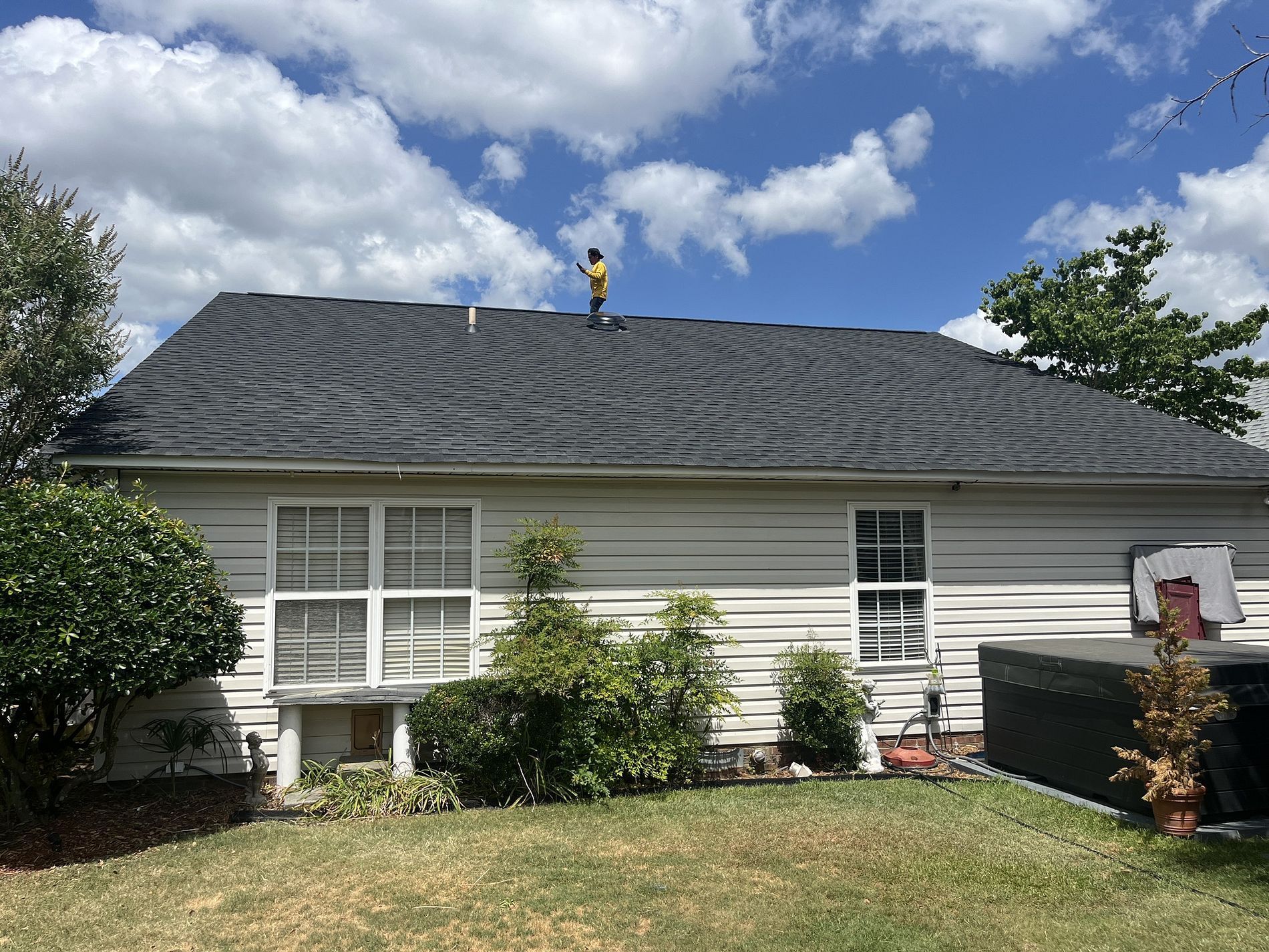 A man is standing on the roof of a house.