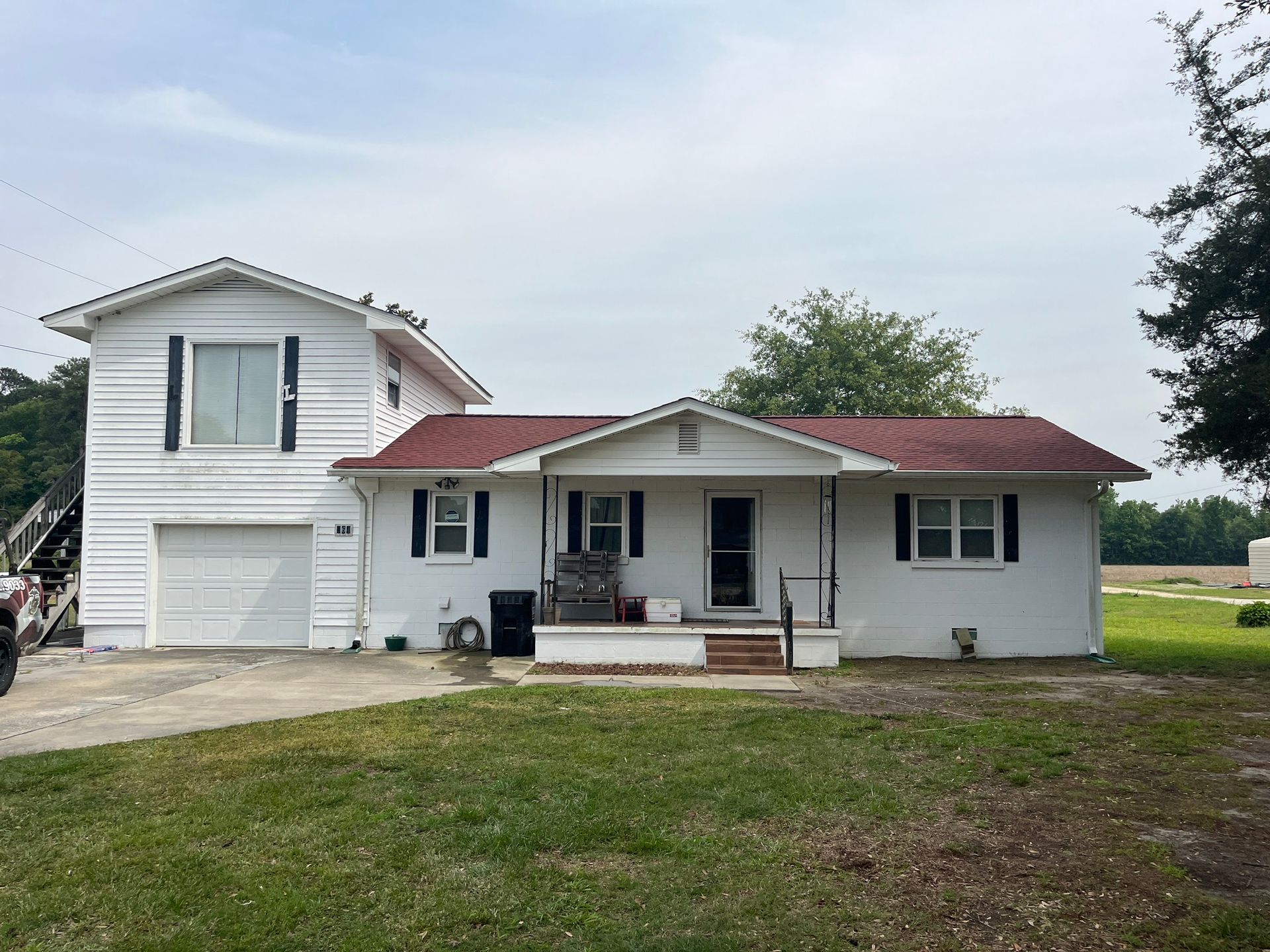A white house with a red roof is sitting on top of a lush green field.