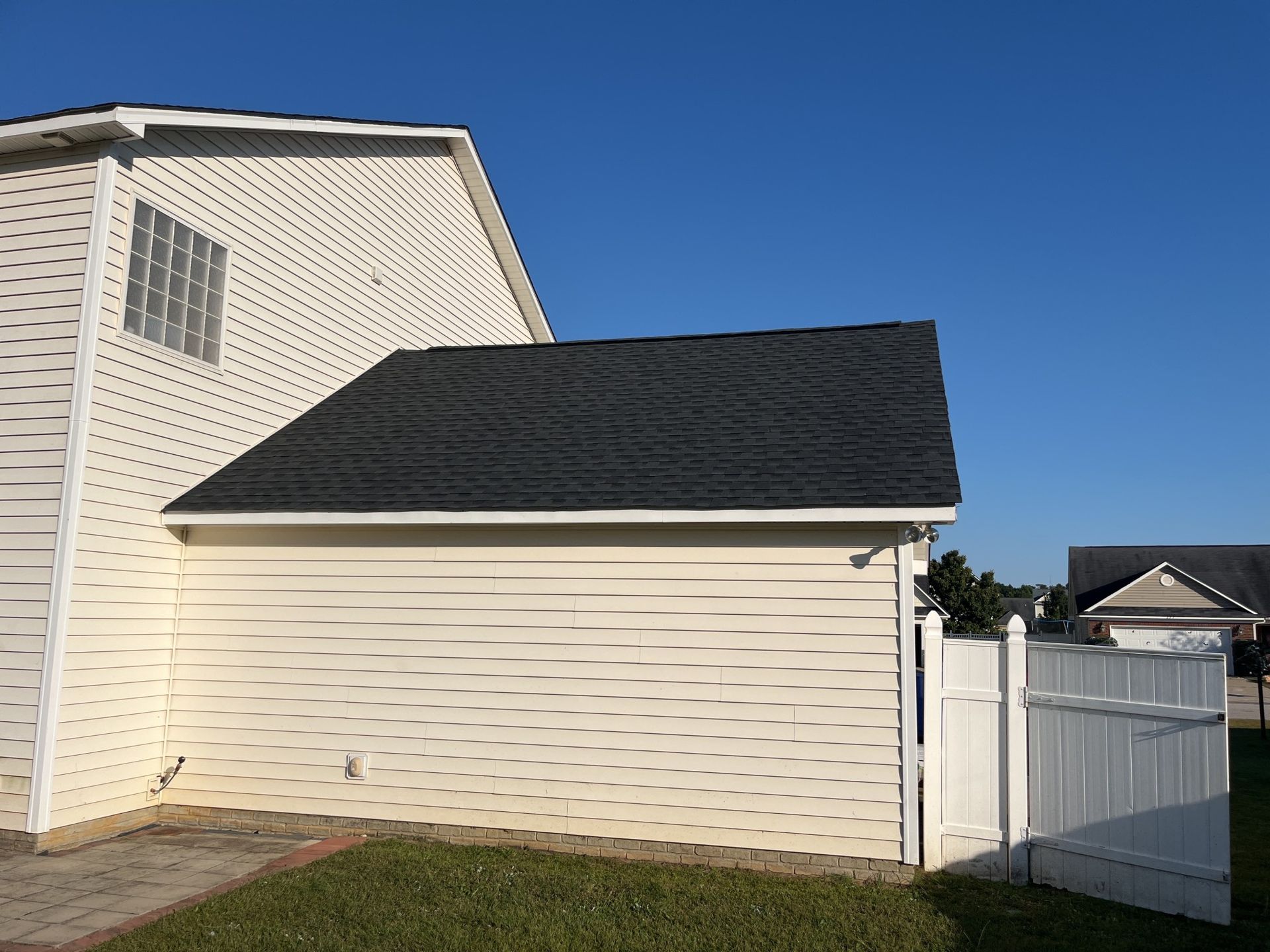 A white house with a black roof and a white fence