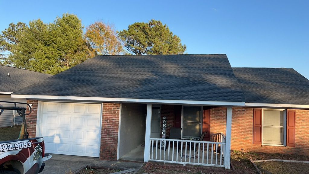 A jeep is parked in front of a brick house with a black roof.