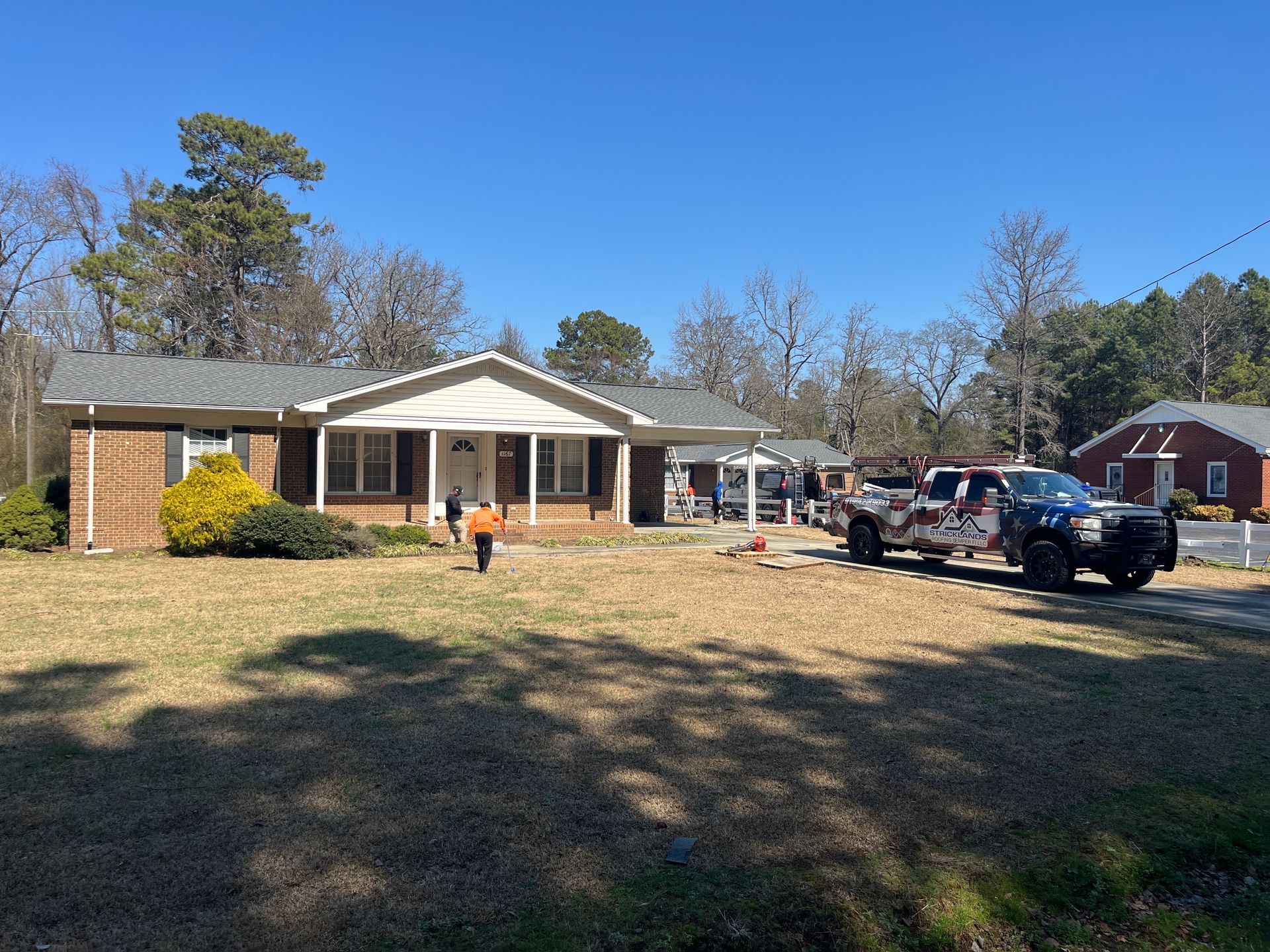 A large white house with a gray roof and a palm tree in front of it.