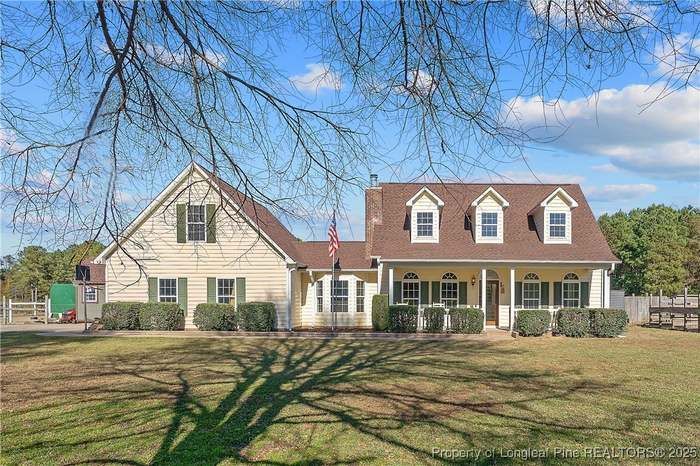 A large white house with a gray roof and a palm tree in front of it.
