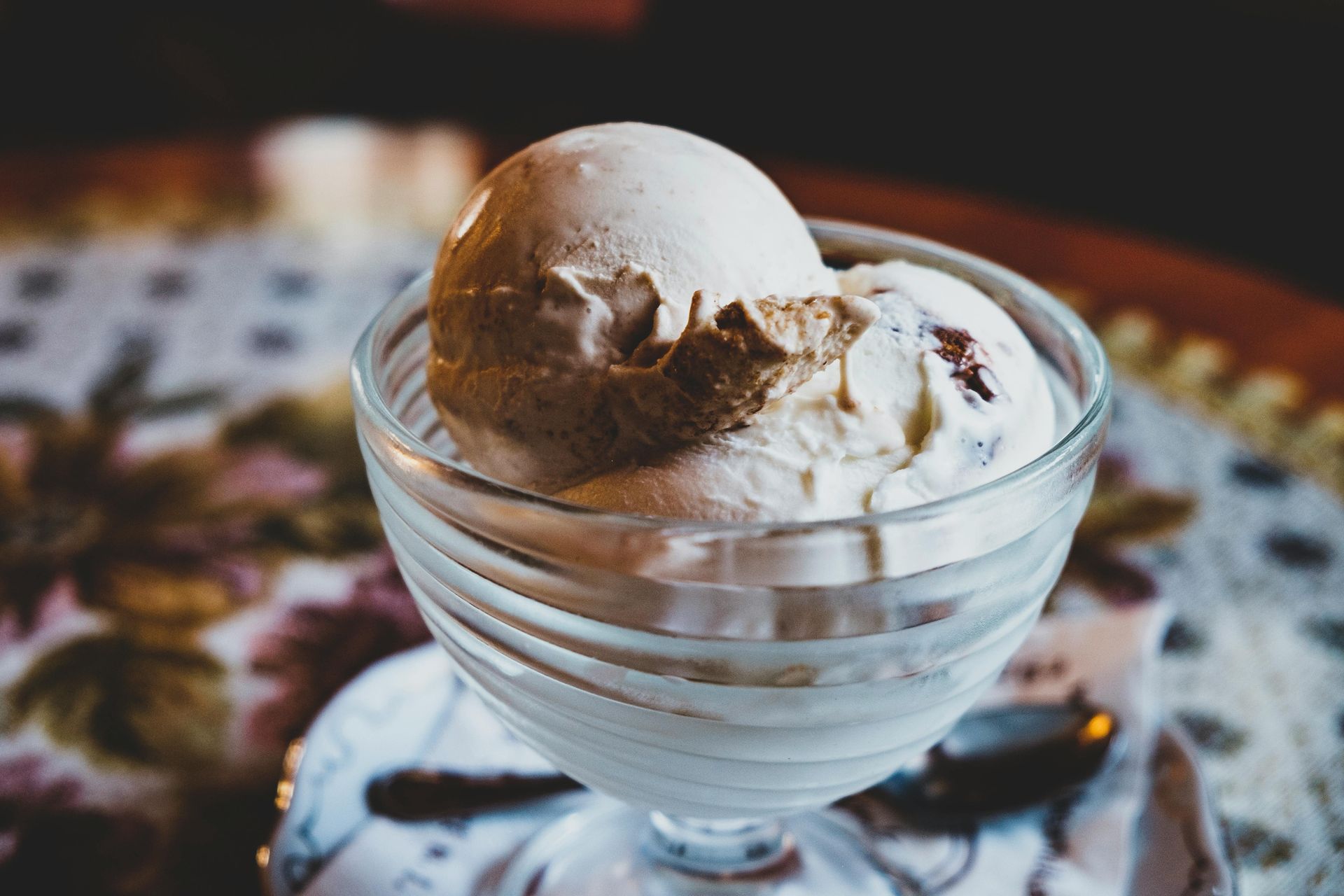 A glass bowl filled with ice cream and a spoon on a table.