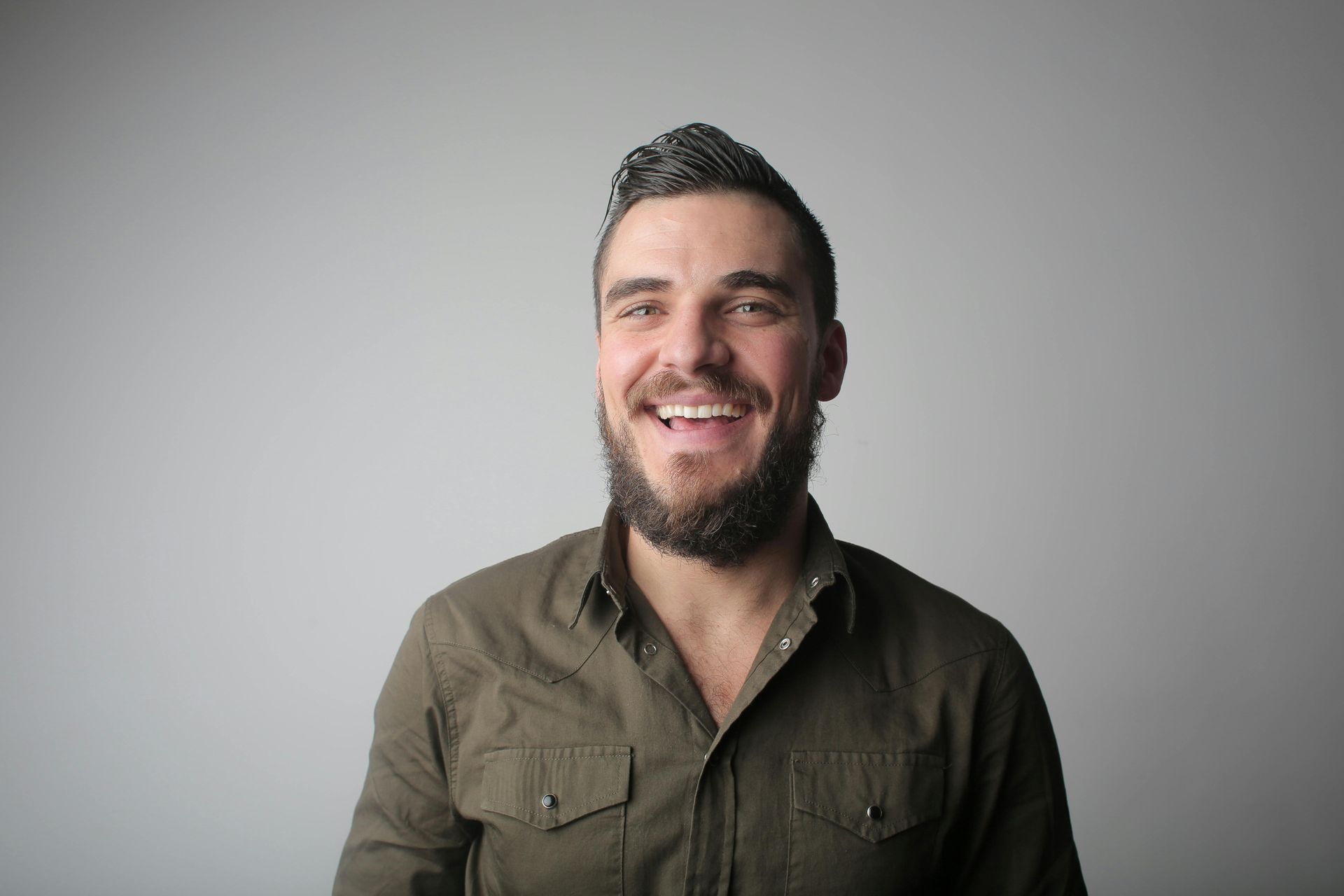 A man with a beard is smiling and looking at the camera.