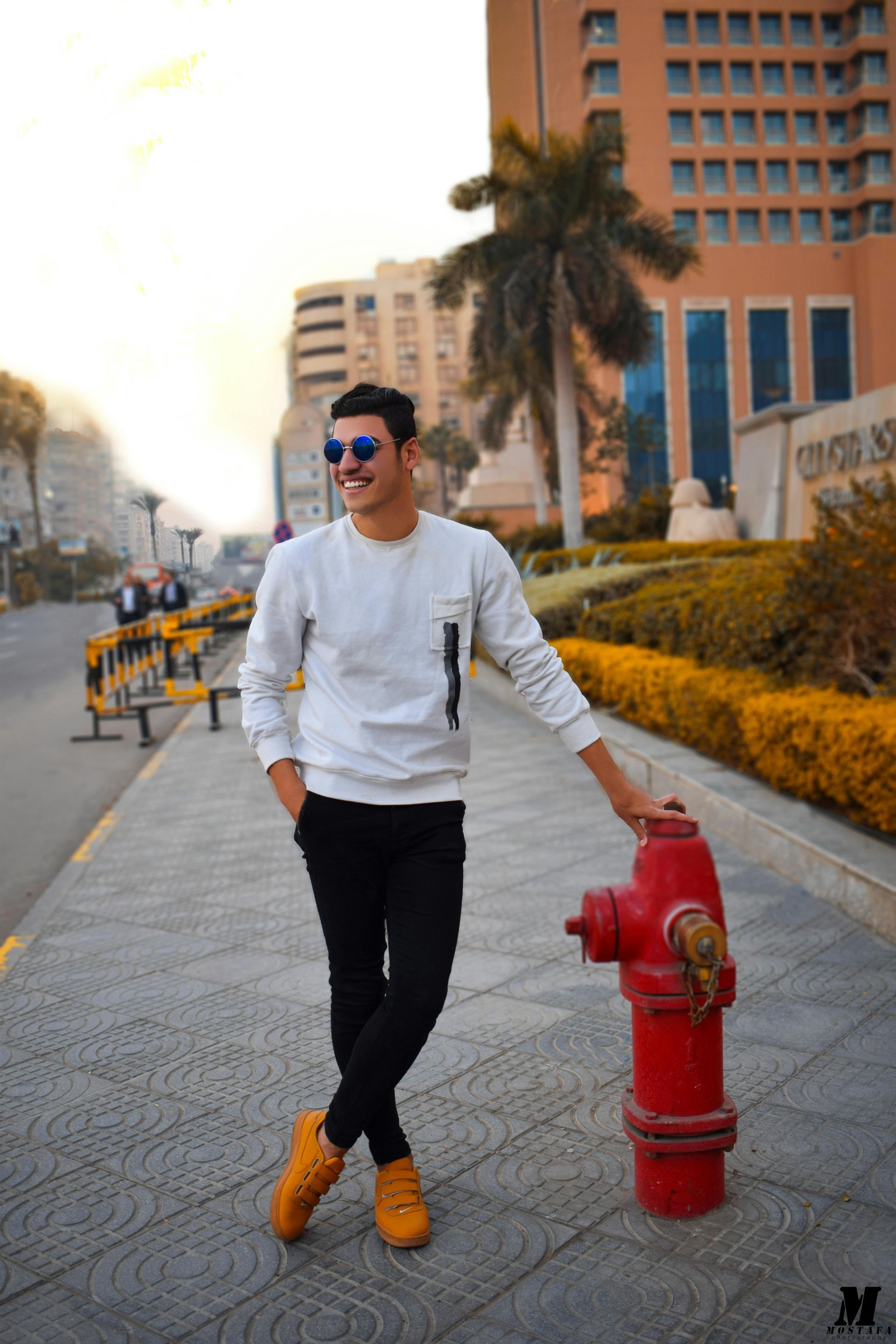 A man is standing next to a red fire hydrant on a sidewalk.