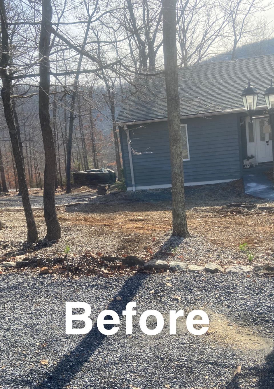 A gravel driveway in front of a blue-sided cabin, trees in the background, labeled 