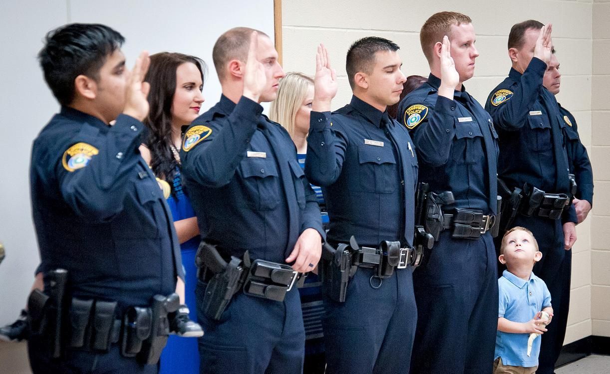 Men standing in line with one hand in the air being sworn in as police officers
