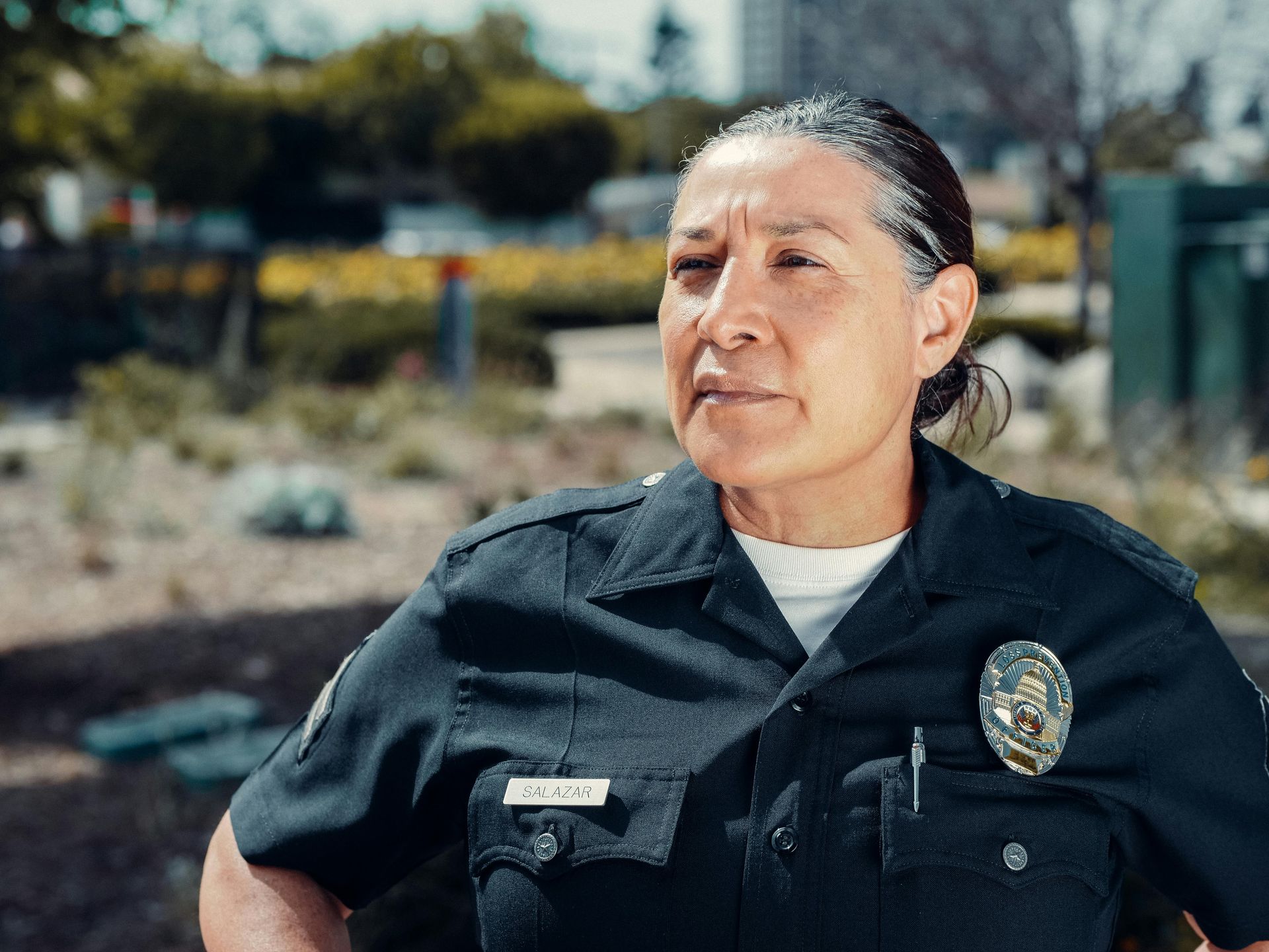 A woman in a police uniform is standing in a park.