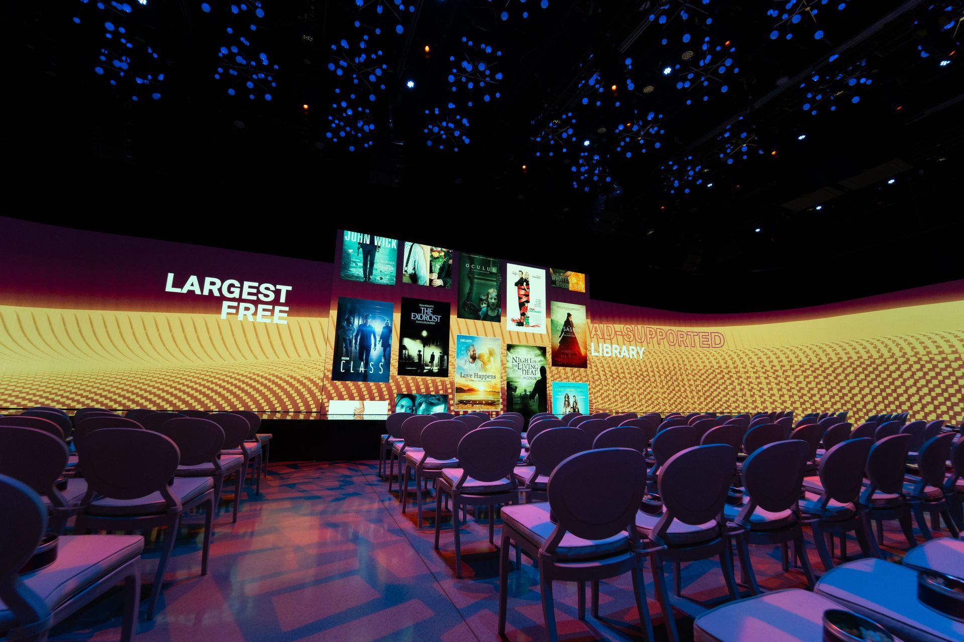 A large auditorium with rows of chairs and a large screen that says largest free