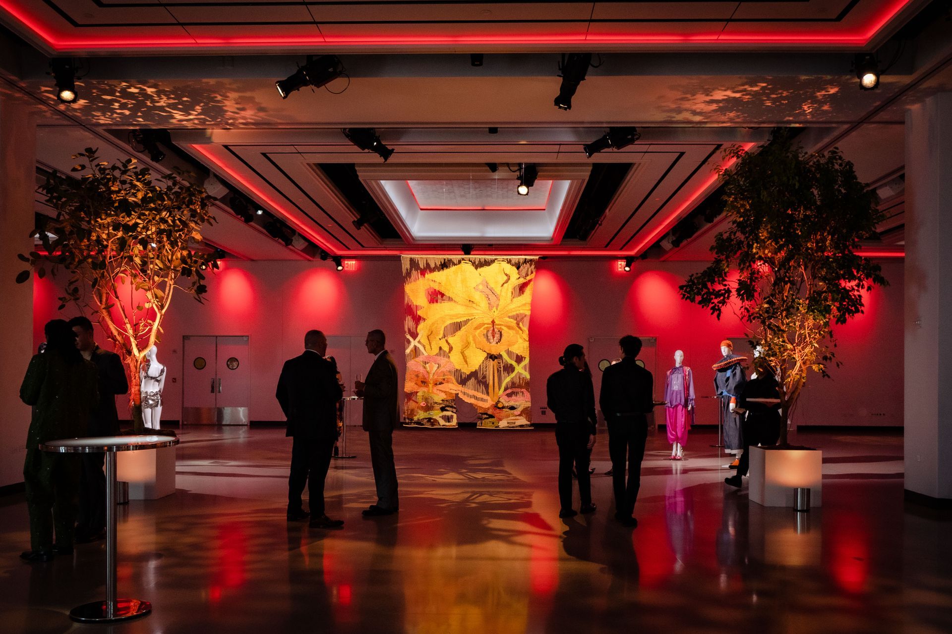 A group of people are standing in a room with red lights.