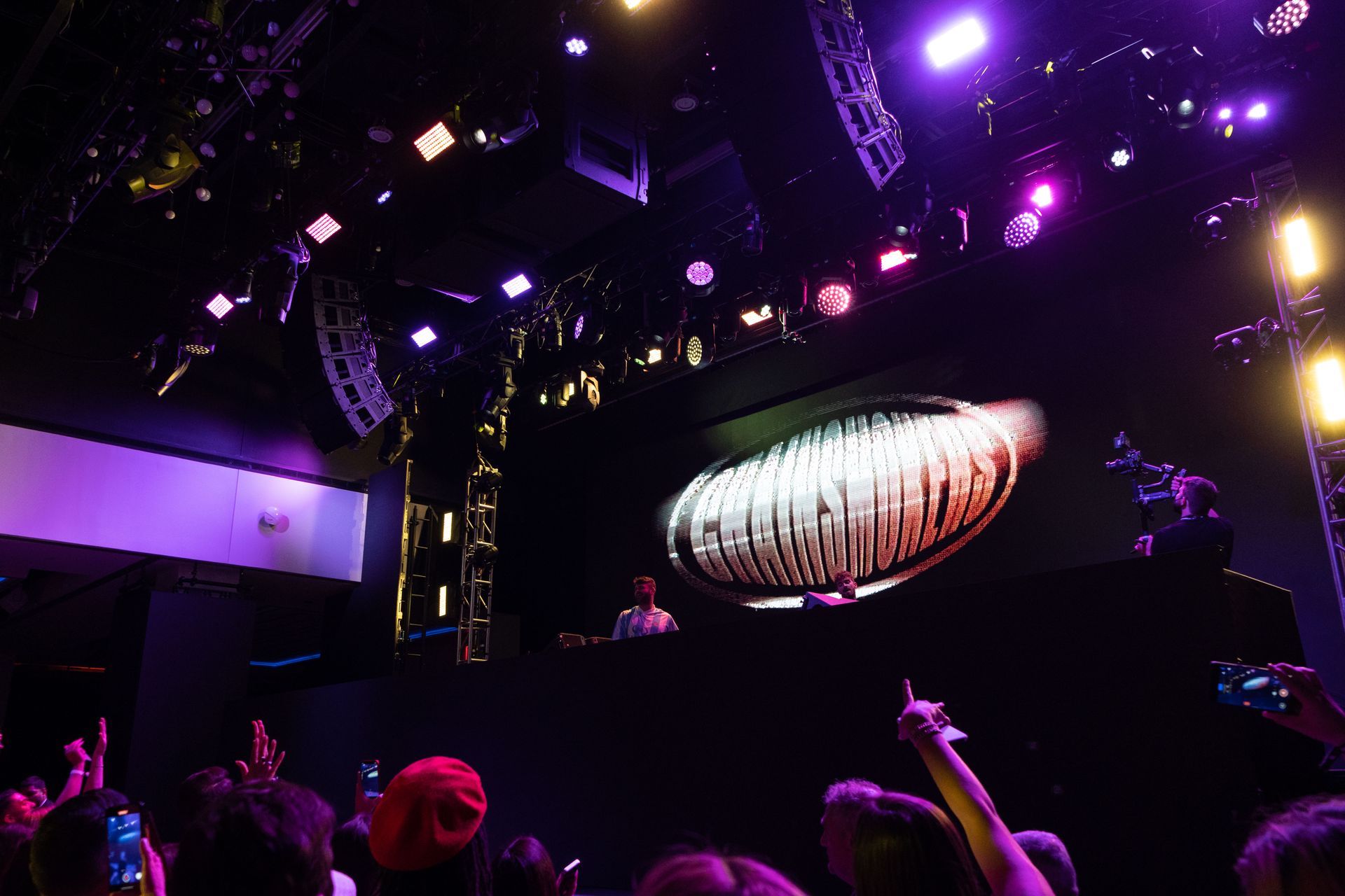 A crowd of people are watching a dj on stage at a concert.