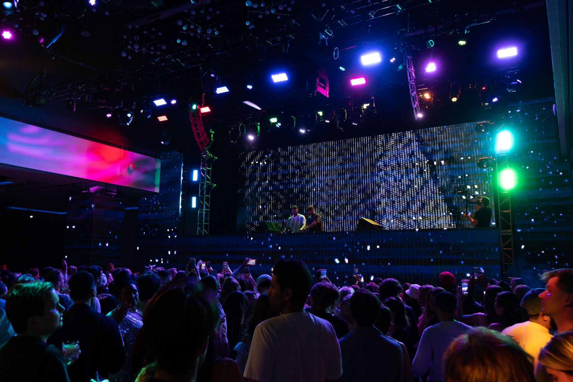 A crowd of people are standing in front of a stage at a concert.