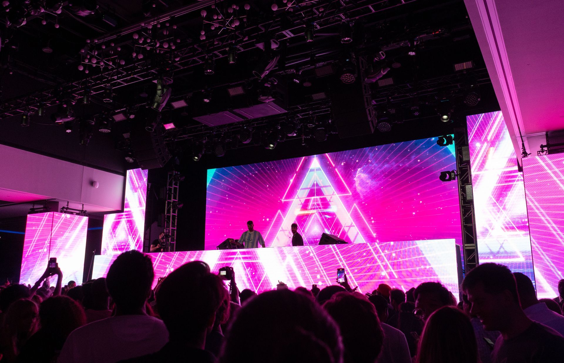 A crowd of people are watching a dj on stage at a concert.