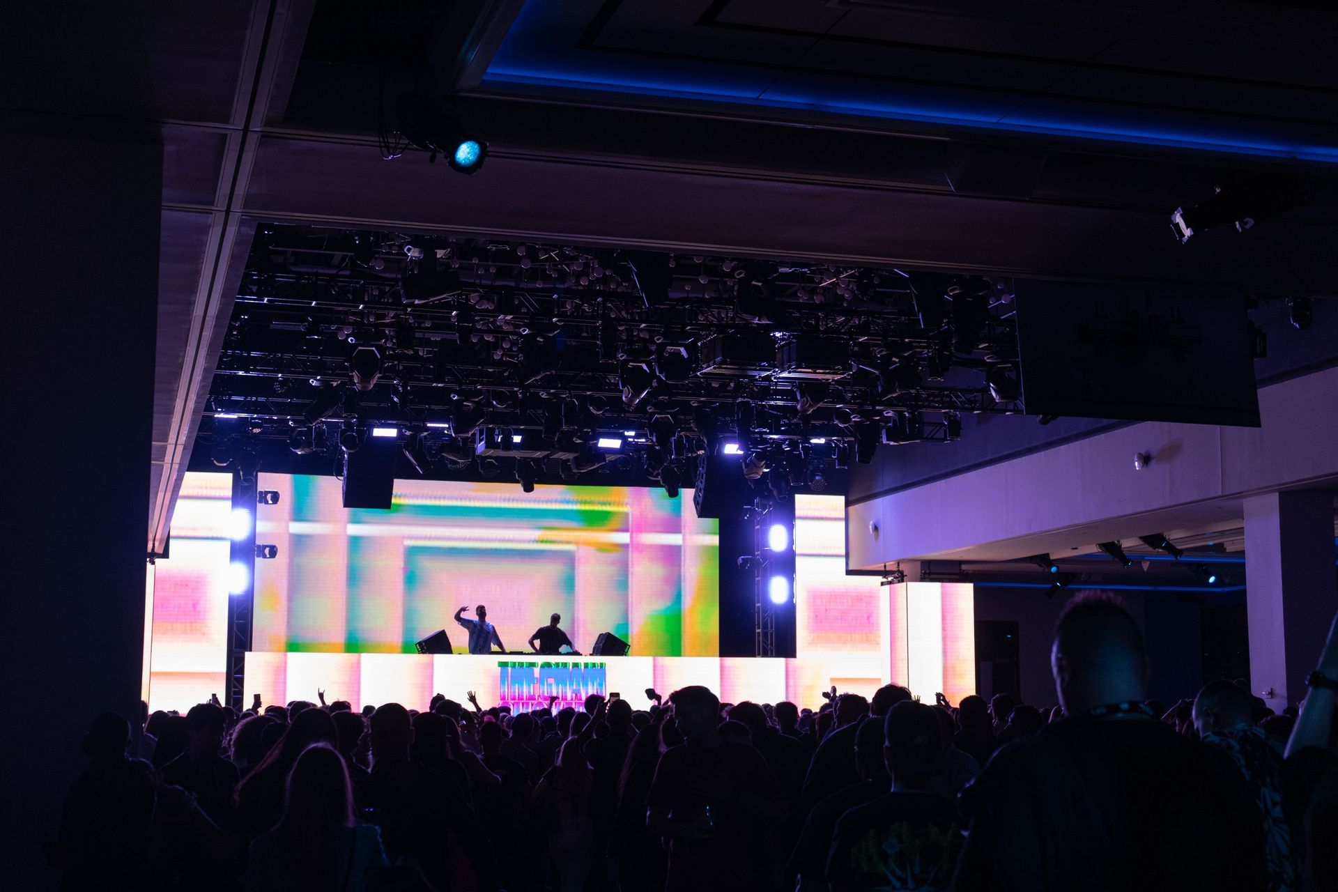A crowd of people are sitting in front of a stage at a concert.