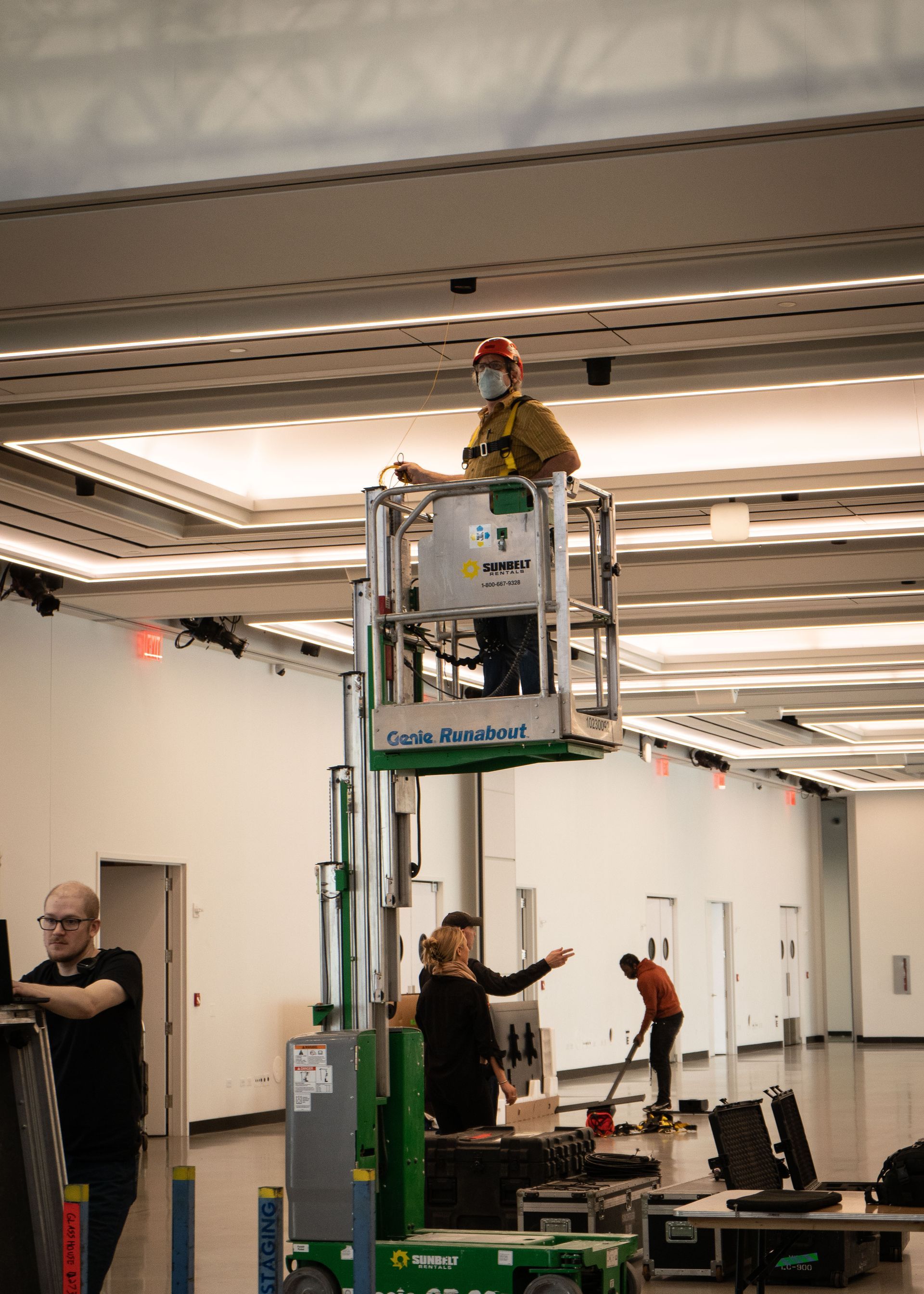 A man is standing on a lift in a large room.