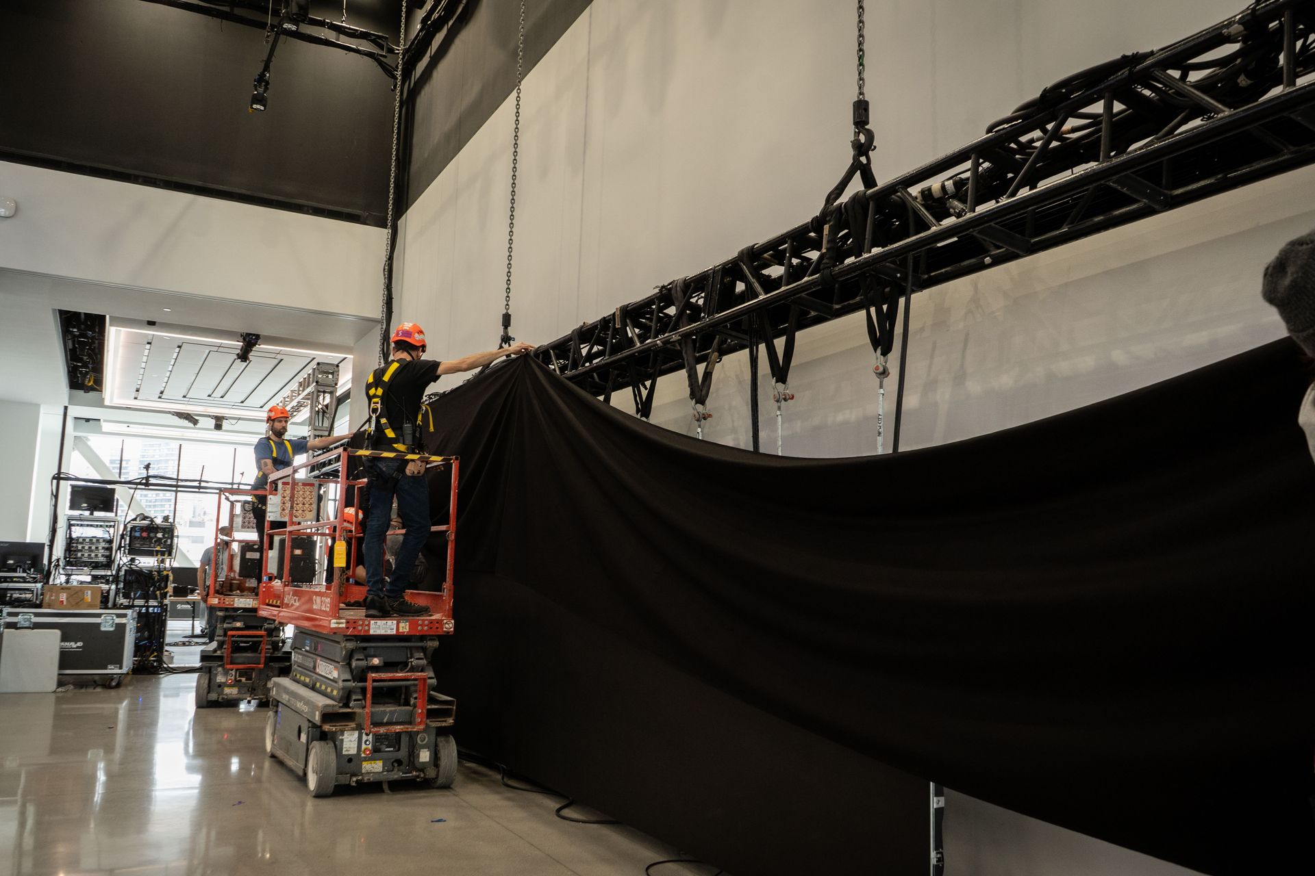 A man is standing on a scissor lift holding a black cloth.