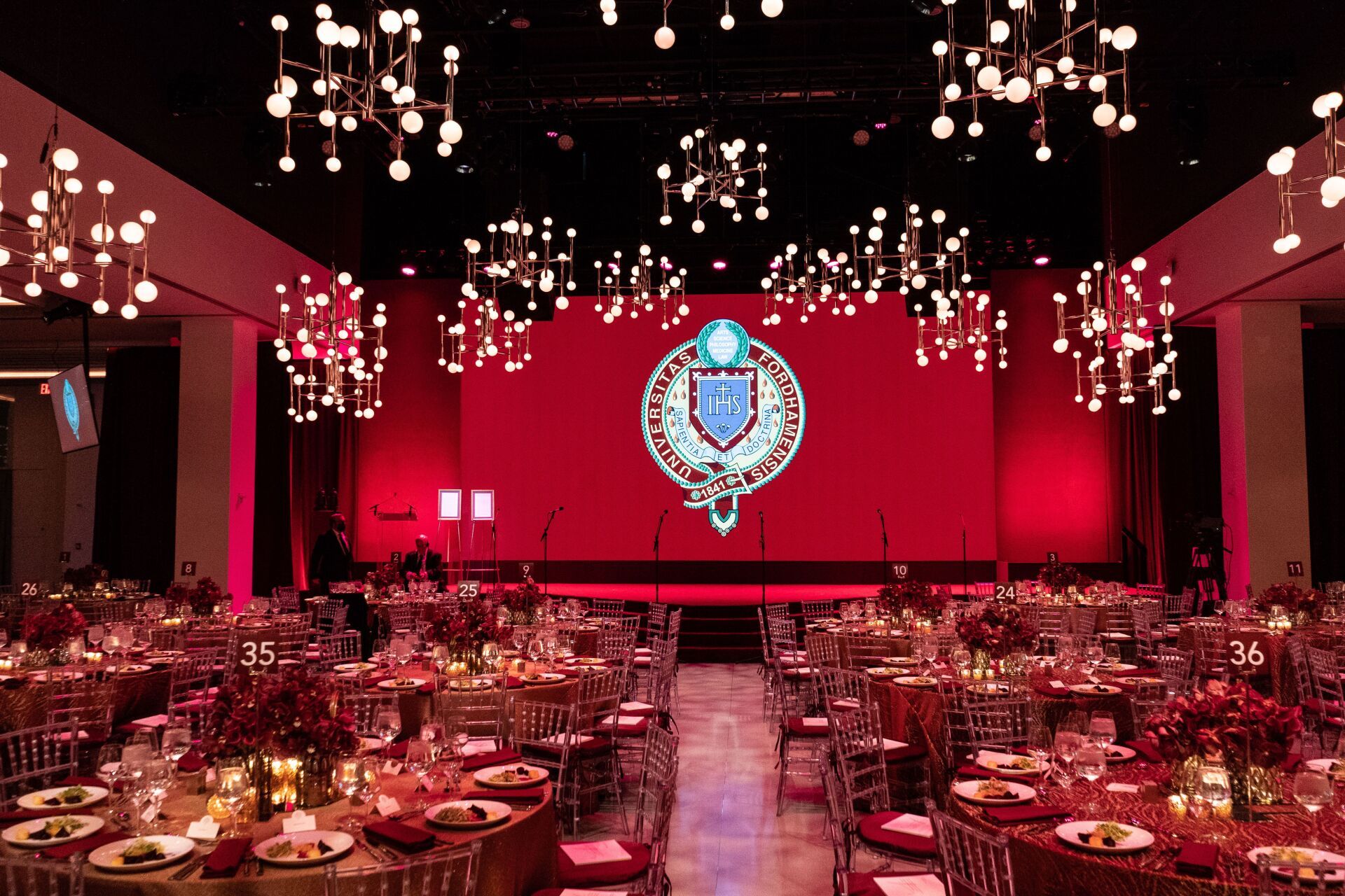 a large room filled with tables and chairs and a large screen .
