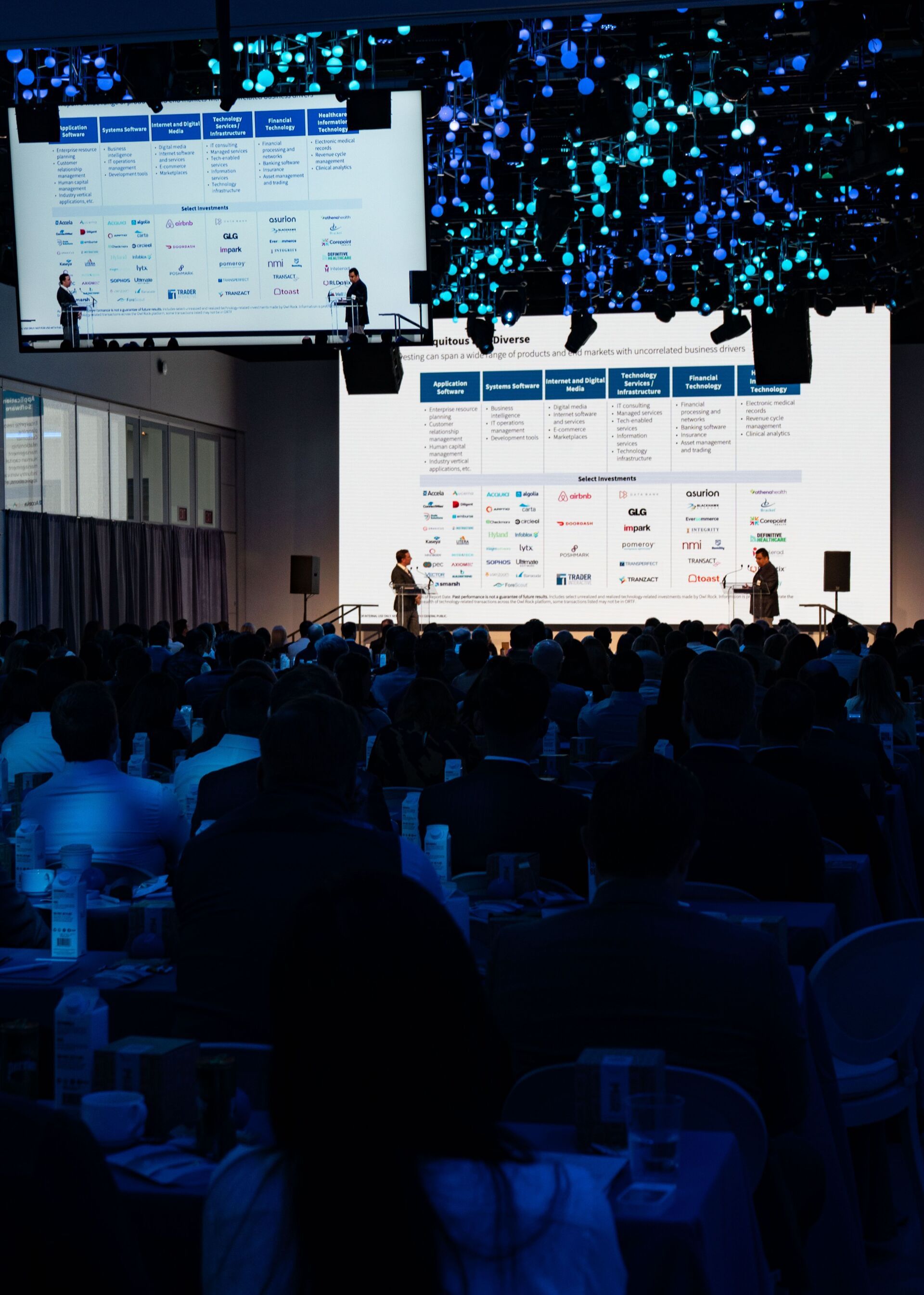 a large group of people are sitting in front of a large screen at a conference .