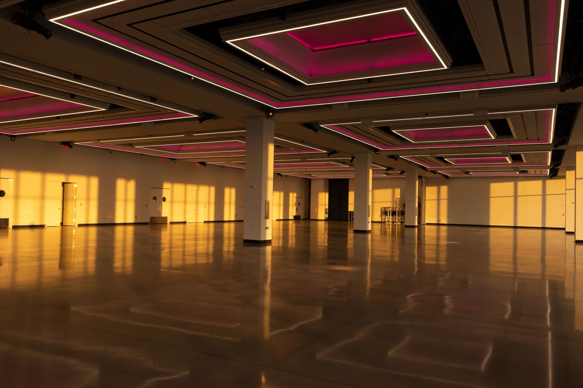 a large empty room with pink lights on the ceiling