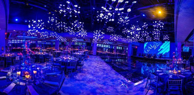 a large room filled with tables and chairs with blue lights on the ceiling .