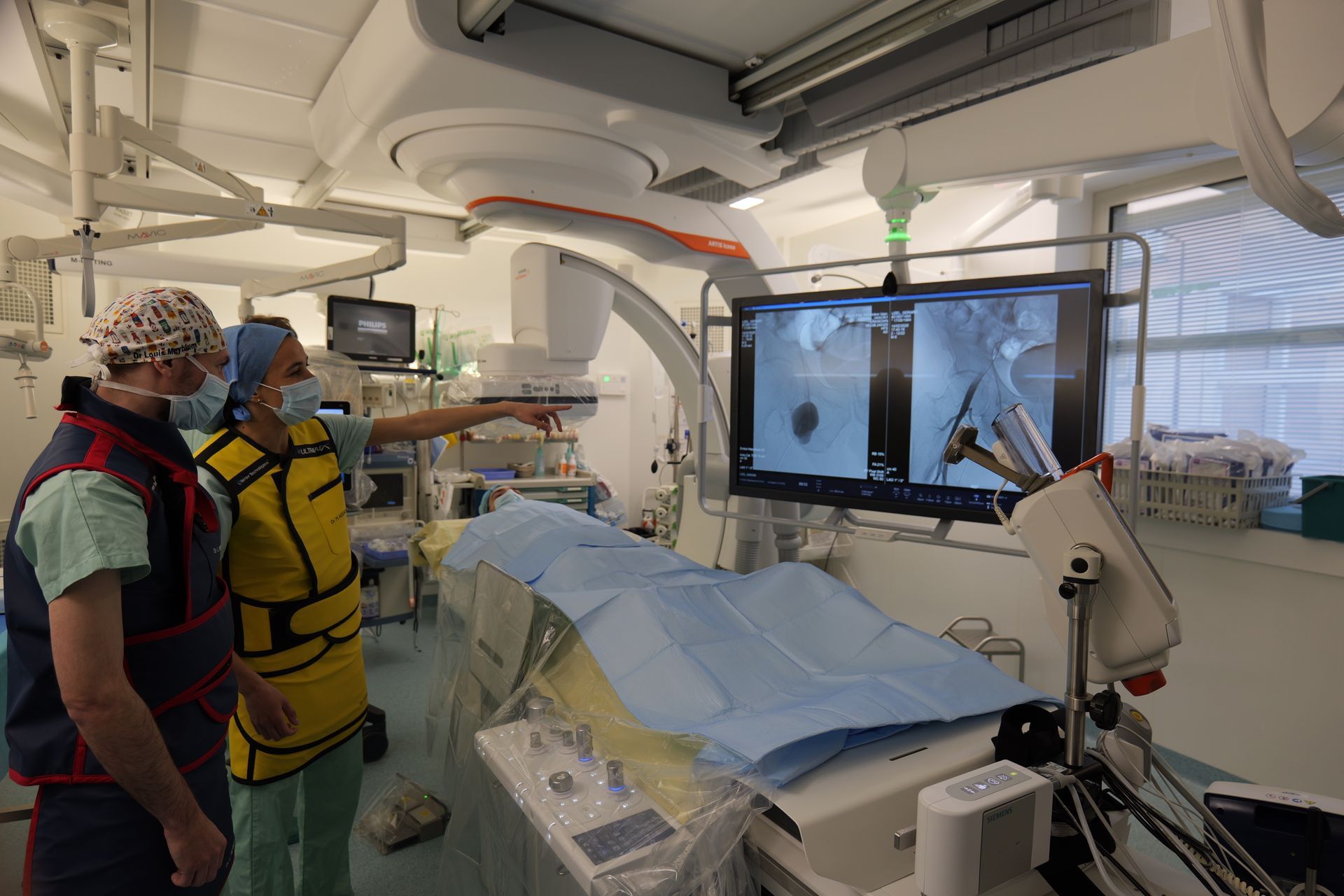 Deux médecins sont debout dans une salle d'opération et regardent un écran.