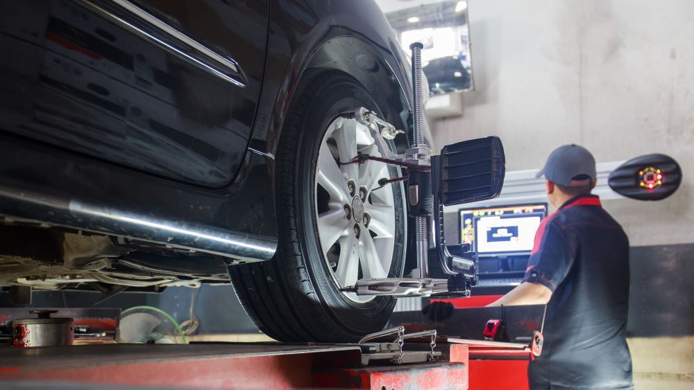A Man is Adjusting a Car Tires in a Garage — P & R Automotive Services in Pialba, QLD 