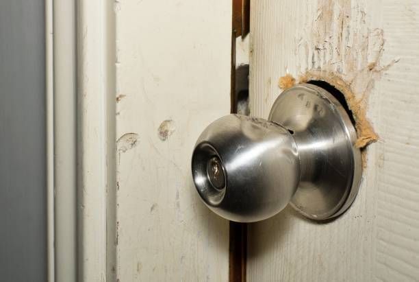 The modern doorknob was broken from a break-in attempt, and the door was cracked open.