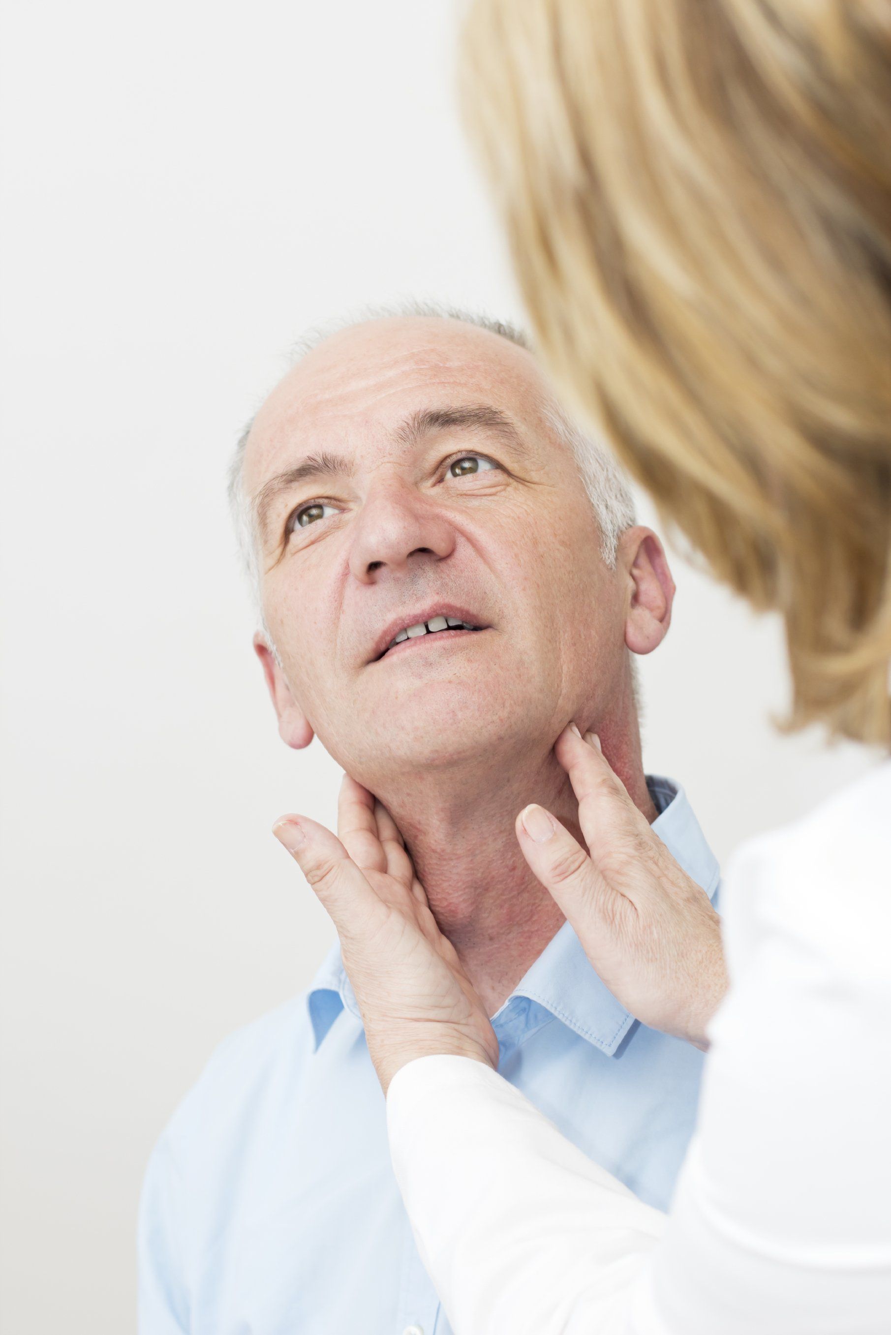 Woman doctor checking older mans thyroid