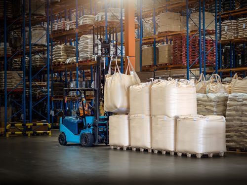 A forklift is carrying bags in a warehouse.