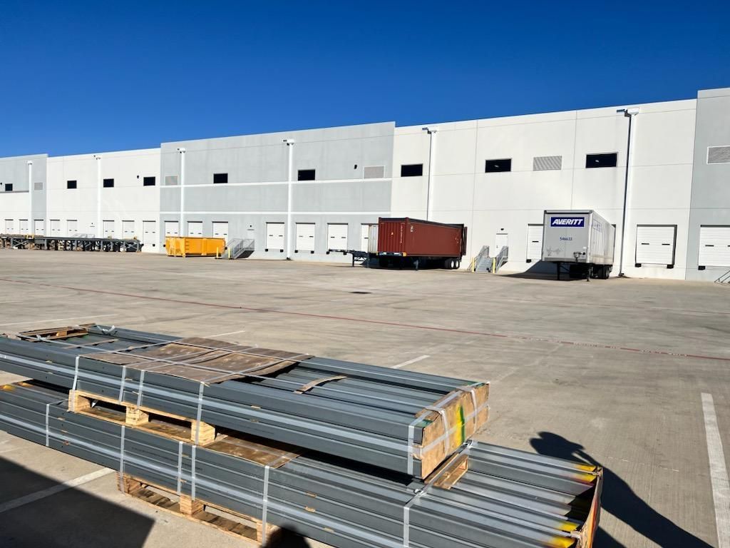 A warehouse with a lot of pallets in front of it