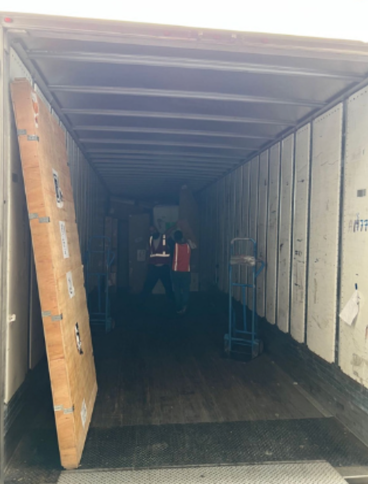 A man is loading a large piece of wood into a truck.