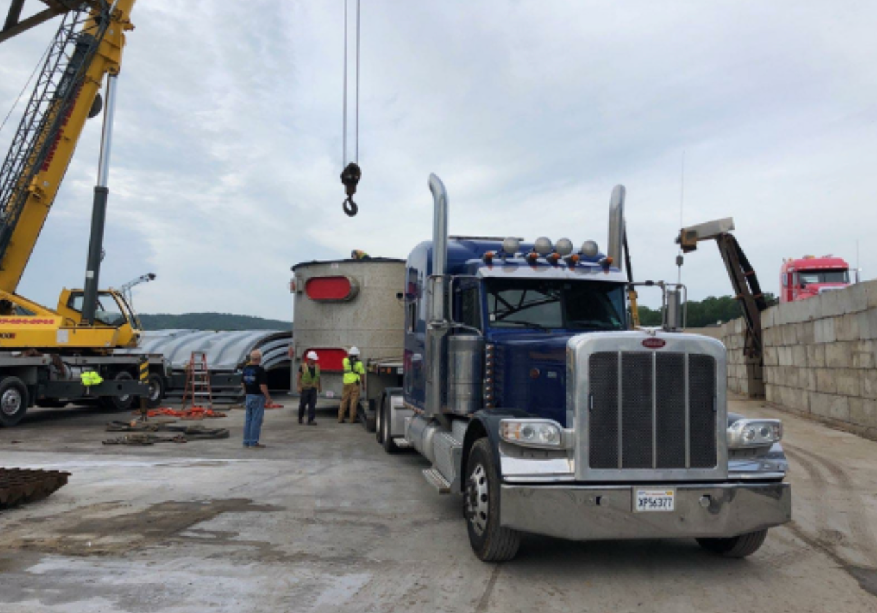 A blue peterbilt semi truck is being lifted by a crane.