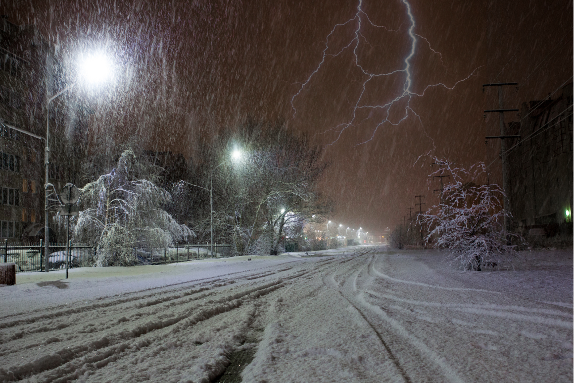 Lightning strikes in the night sky over a snowy street thundersnow