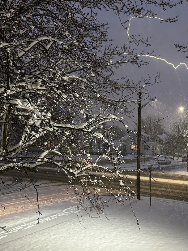 A snowy street with a lightning strike in the background