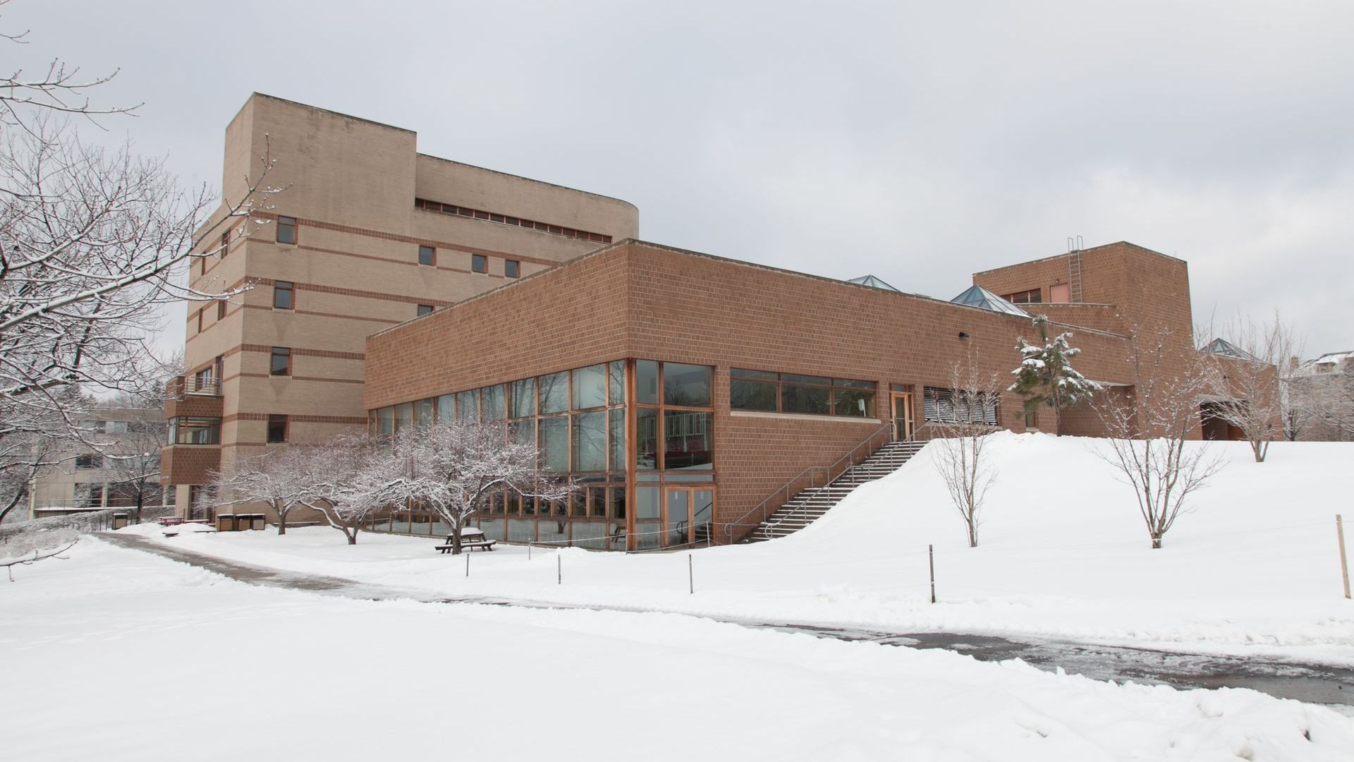 A large brick building with stairs leading up to it is covered in snow.