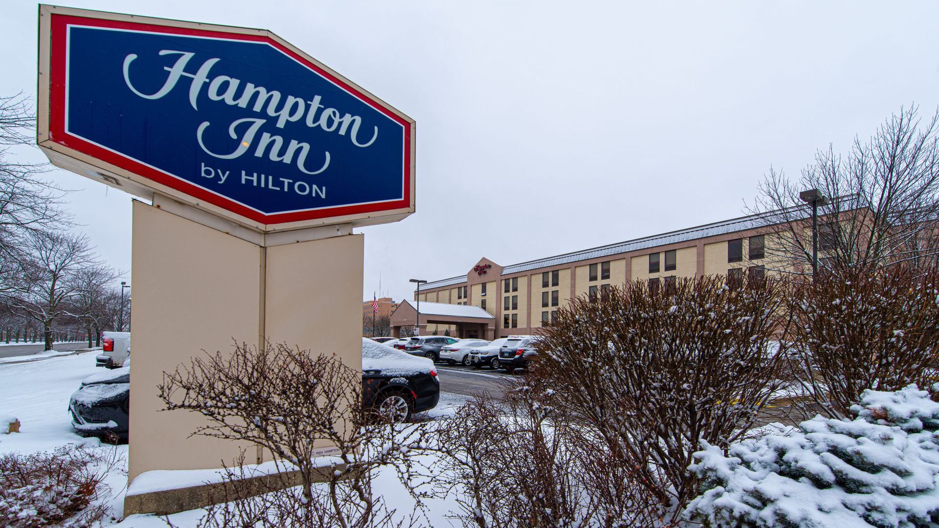 A sign for hampton inn by hilton is surrounded by snow